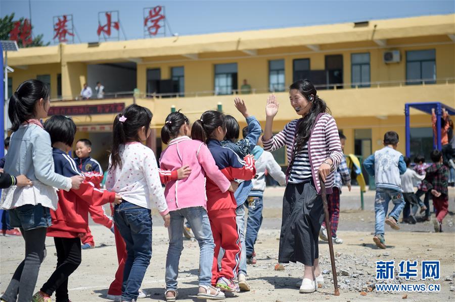 5月16日,李元芳在课间休息时与孩子们一起做游戏。